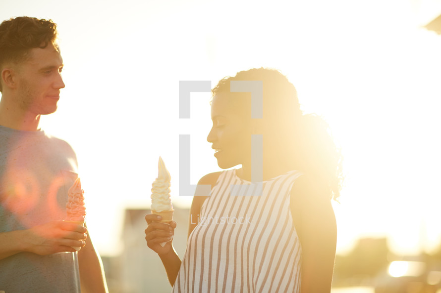 a man and a woman eating ice cream at sunset 