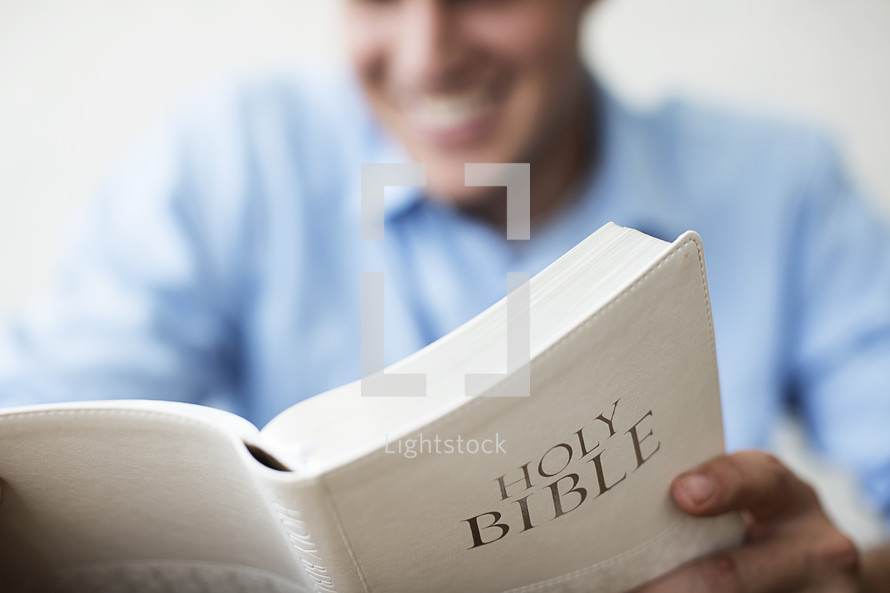 Smiling man reading the Bible.