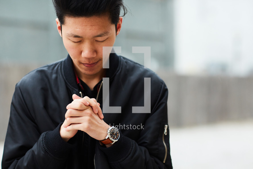 teen boy with head bowed in prayer 