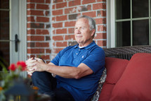 a smiling man sitting on a porch relaxing 