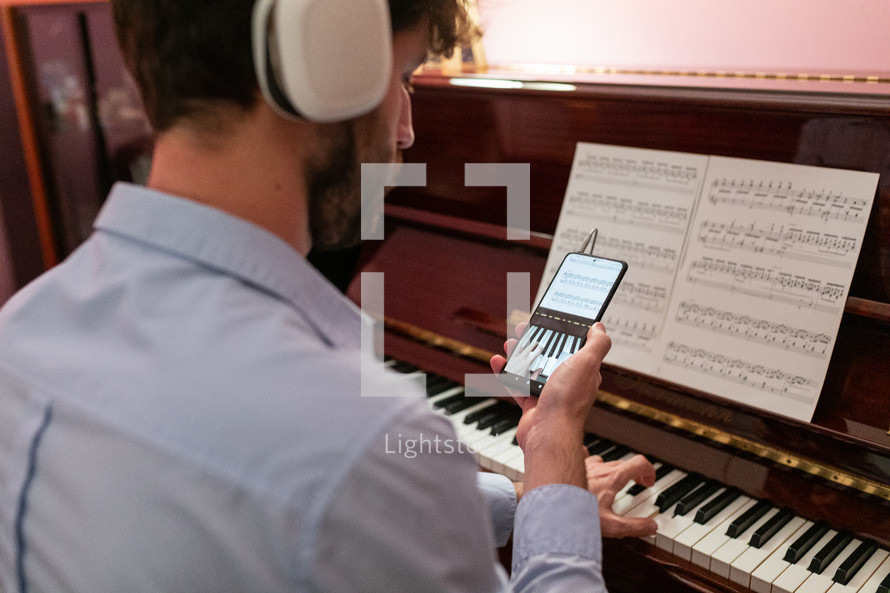 Man teaching piano lessons with remote smartphone connection