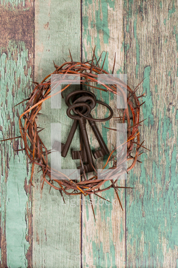 crown of thorns and skeleton keys on a green wood background 