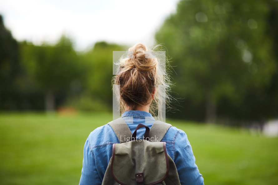 a woman with a backpack standing with her back to the camera 