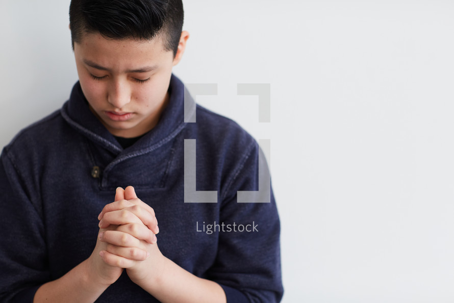 Asian boy with head bowed in prayer