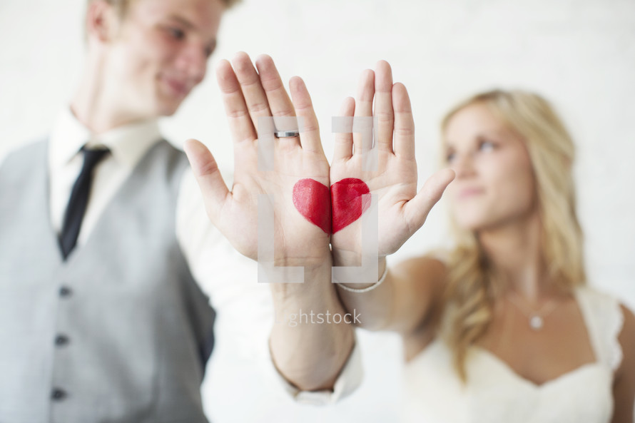 bride and groom with a red heart painted on their hands 