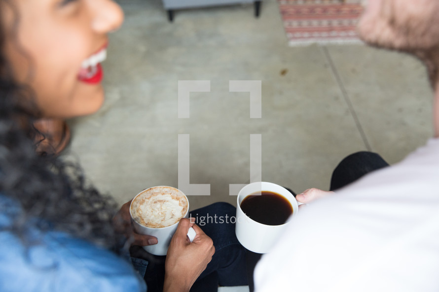 a couple holding mugs of hot cocoa and talking