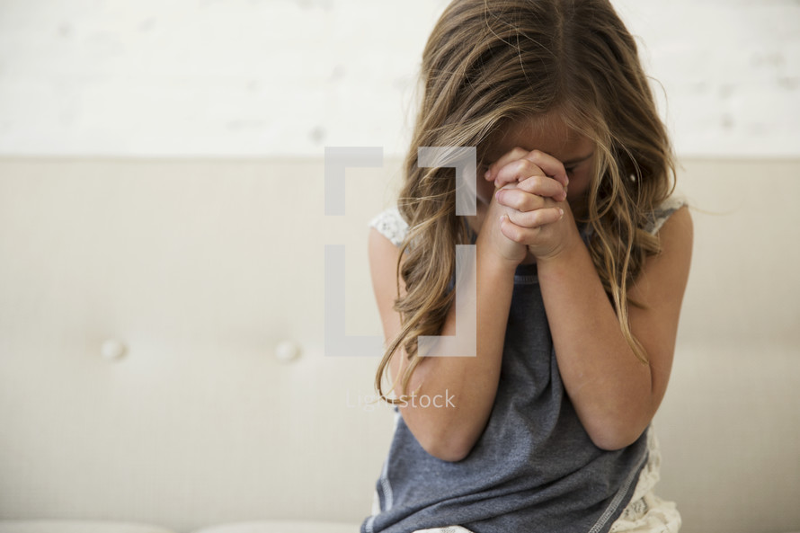 a girl child with praying hands 