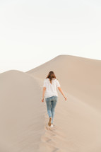 a woman standing on desert sand dunes 
