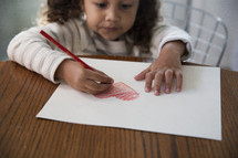 a girl child coloring a heart 