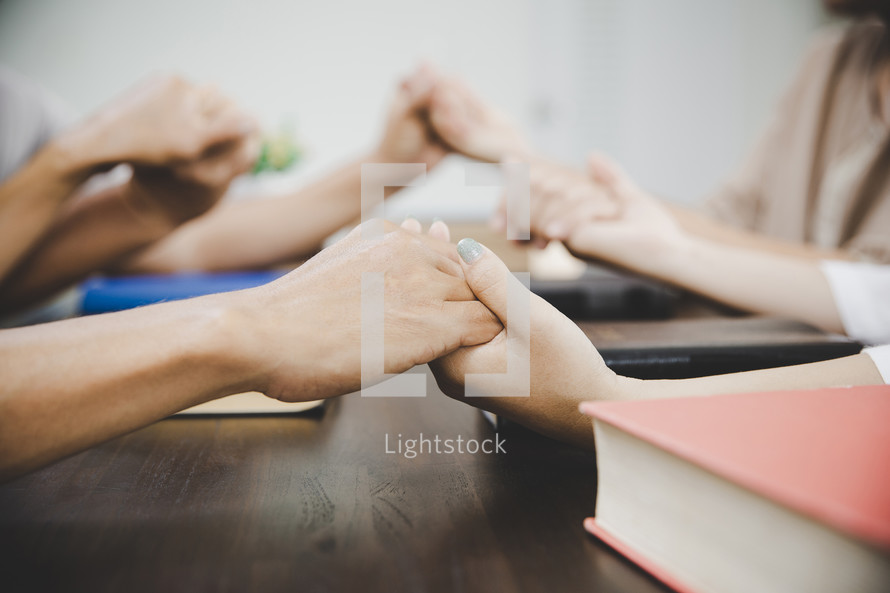 Group of people praying together and holding hands