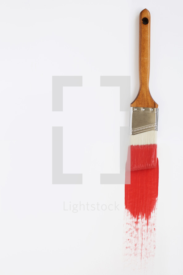 A paint brush with red paint on a white background.