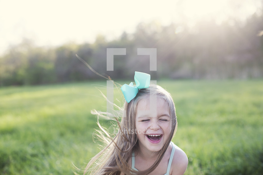 laughing little girl in a field of green grass 