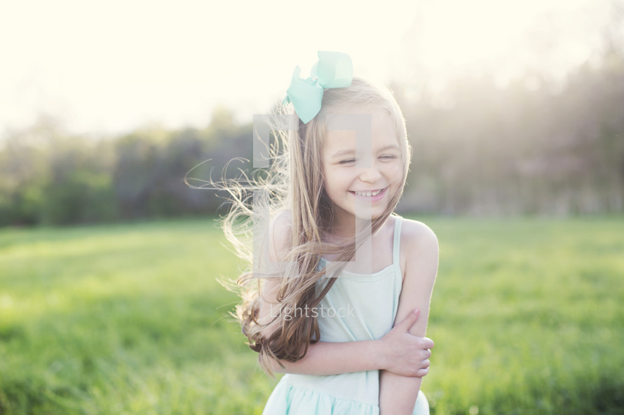 a little girl standing in a field of green grass laughing 