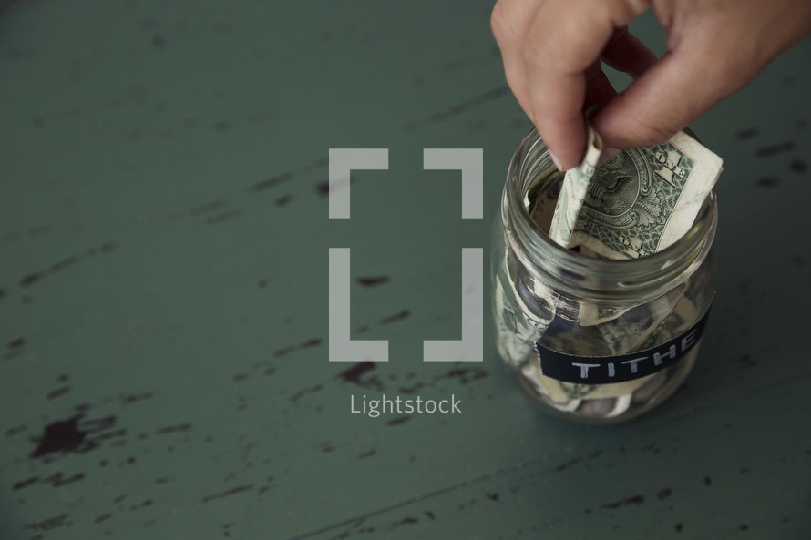 putting money into a tithe savings jar 