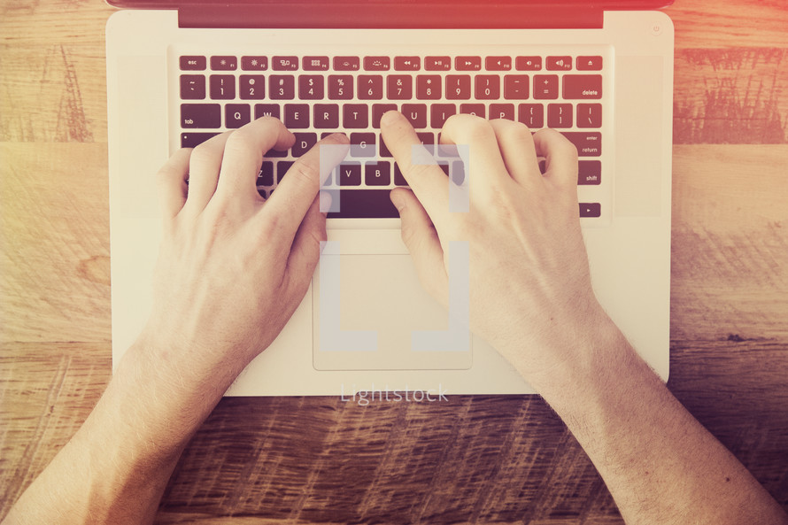 hands typing on a laptop computer on a desk