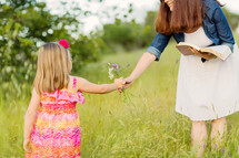 daughter picking flowers and handing them to her mother