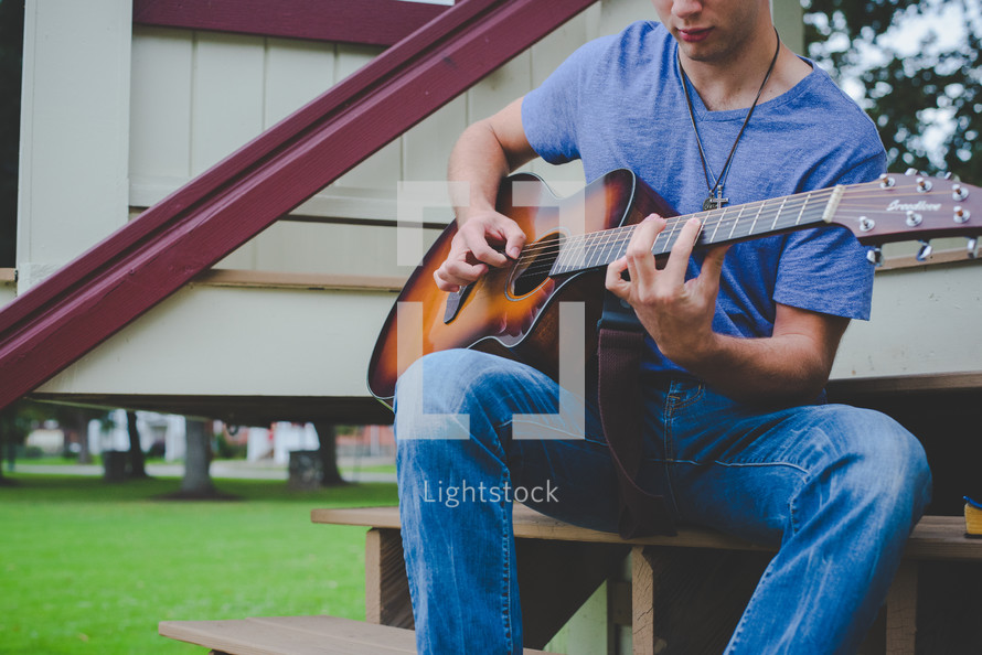 boy playing a guitar outdoors 