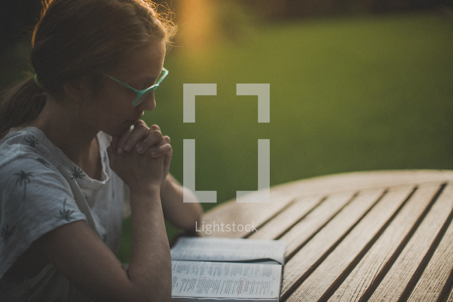 a young woman reading and praying over a Bible 