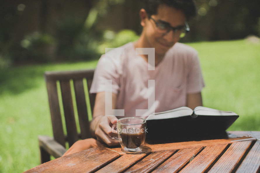 a young man reading a Bible in her backyard 