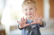toddler boy holding up both hands 