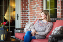 a woman sitting on a porch staring off into space 