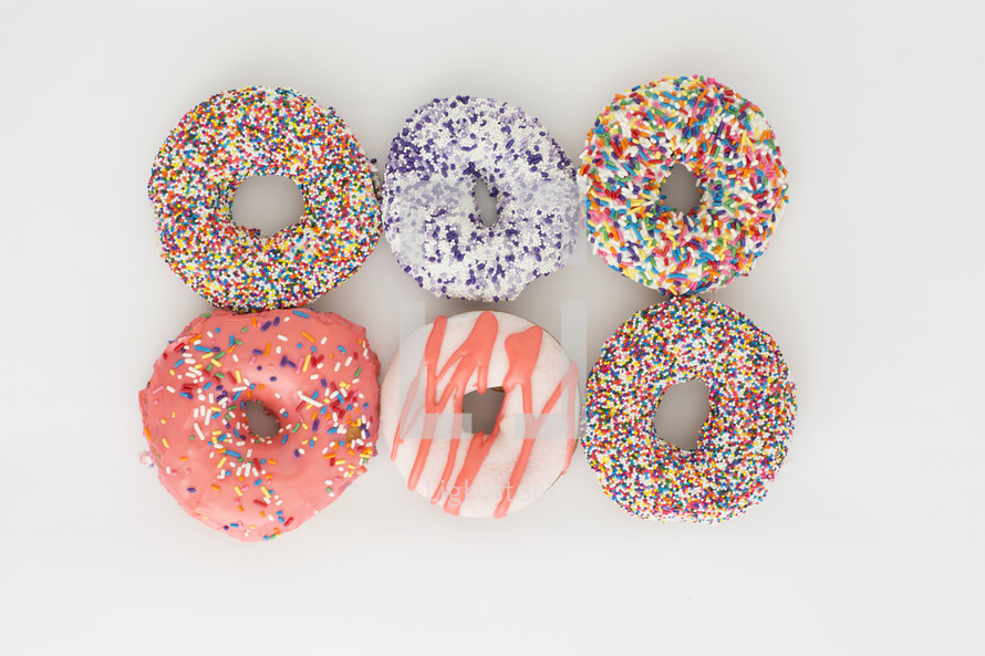 rows of sprinkled donuts on a white background 