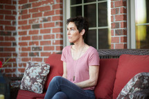 a woman sitting on a porch staring off into space 