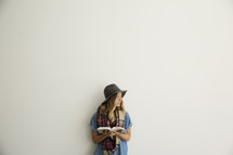 a woman in a plaid shaw and hat holding a Bible 