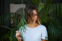 a woman standing in palm leaves 