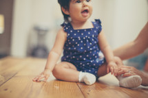 toddler girl sitting on a wood floor 
