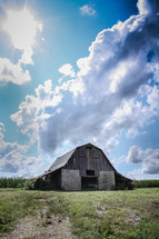 Barn in a field under the clouds.