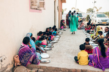 women and children in a village waiting for food 