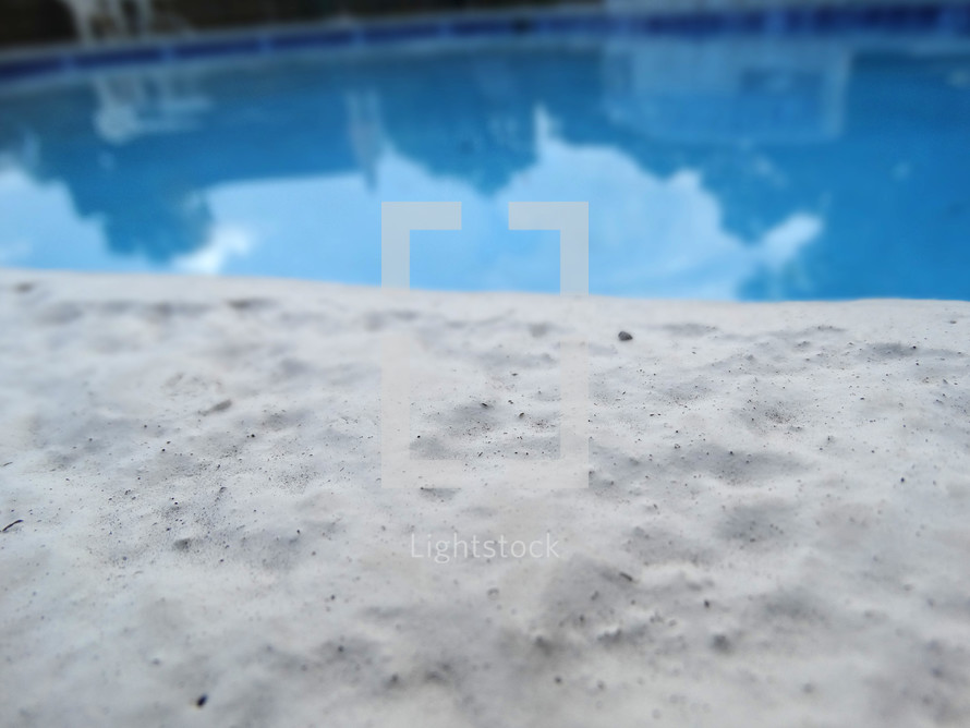 Close up of pool deck edge with blue swimming pool in background