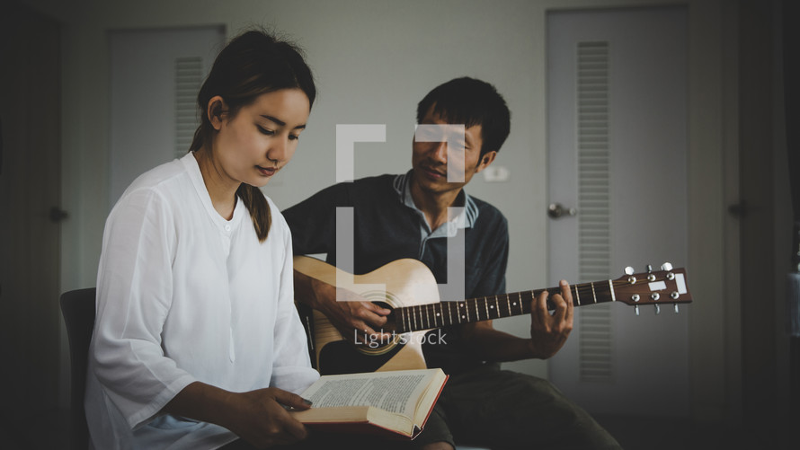 Asian man playing guitar and woman worshiping.
