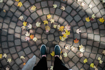 woman standing on fall leaves and a patio 