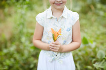 a little girl holding picked flowers 