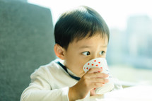 a toddler drinking out of a cup 