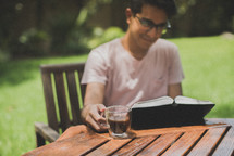 a young man reading a Bible in her backyard 