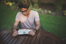 a young man reading a Bible in his backyard 