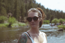woman standing in a river wearing sunglasses 