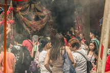 incense and beads around a cross and crowds praying 