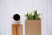 coffee mug, journal, and tulips in a paper bag