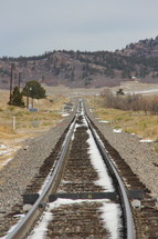 Melting snow on Santa Fe railroad tracks disappearing into the distance, over the horizon
