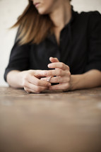 A woman removing her wedding ring from her finger while sitting at a table.