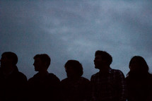 Silhouette of a group of teens at dusk.