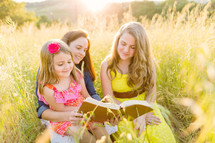 mother and daughter's reading a Bible together outdoors 