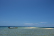 beached boat on a sand bar in tropical water