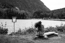 anglers sign near a river and a woman sitting on a bench