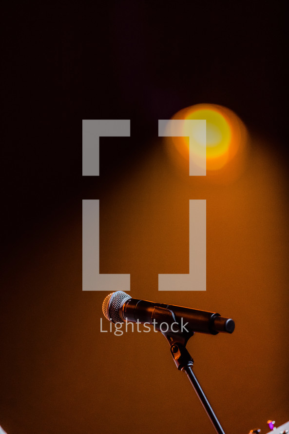 An orange stage light shining on a microphone.
