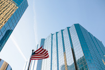 An American flag flying between tall buildings.